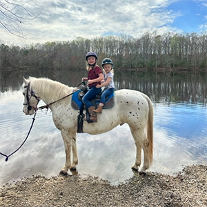 Two little girls riding a riding near a lake